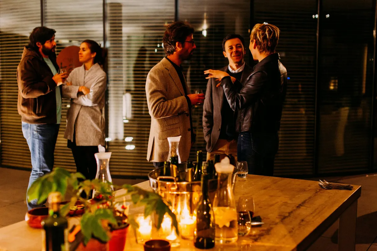 Guests mingling with drinks around a candlelit table at an evening corporate gathering